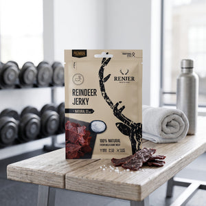 Renjer Reinsdyr Jerky med Sjøsalt på en benk på treningssenteret, med manualer, håndkle og drikkeflaske i bakgrunnen, AI-generert bilde