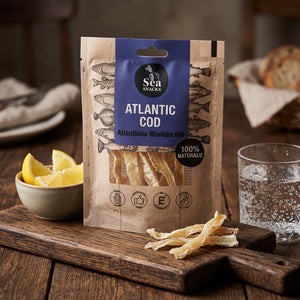 Sea Snacks tørket torsk fra Atlanterhavet på en mørk fjøl med sitronbåter og et glass farris, AI-generert bilde