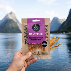 Hånd som holder Sea Snacks tørket blekksprut foran et fjordlandskap, AI-generert bilde