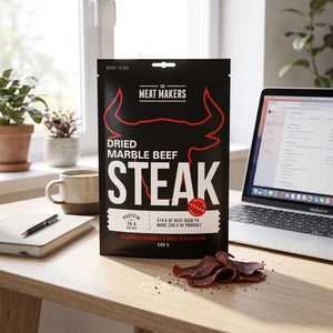 Meat Makers Tørket Marmorert Oksefilet på skrivebordet ved siden av laptop, kaffekopp og notatbok, AI-generert bilde