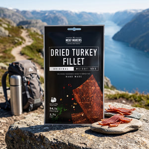Meat Makers Tørket Kalkun Filet på en stein ved en fjellsti høyt over fjorden, med ryggsekk og termos, AI-generert bilde