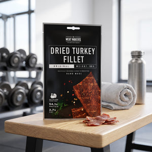 Meat Makers Tørket Kalkun Filet på en benk på treningssenteret, med manualer, håndkle og drikkeflaske i bakgrunnen, AI-generert bilde